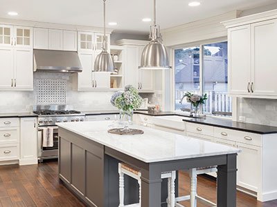 Modern kitchen with white cabinets, dark gray island, and silver hanging lights