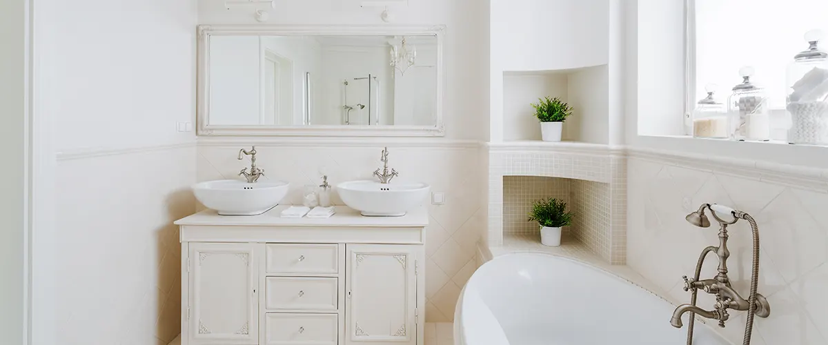 A white bathroom with a tub and golden faucet