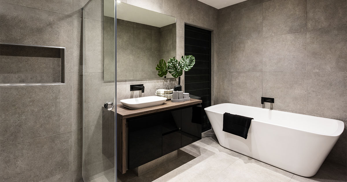 A modern bath with a tub, a vanity, and a glass shower with large gray tile walls
