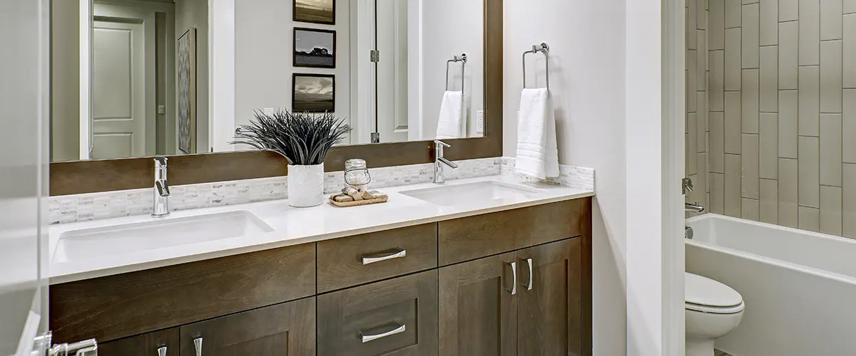 A beautiful wood vanity with a marble countertop and a plant on top of it