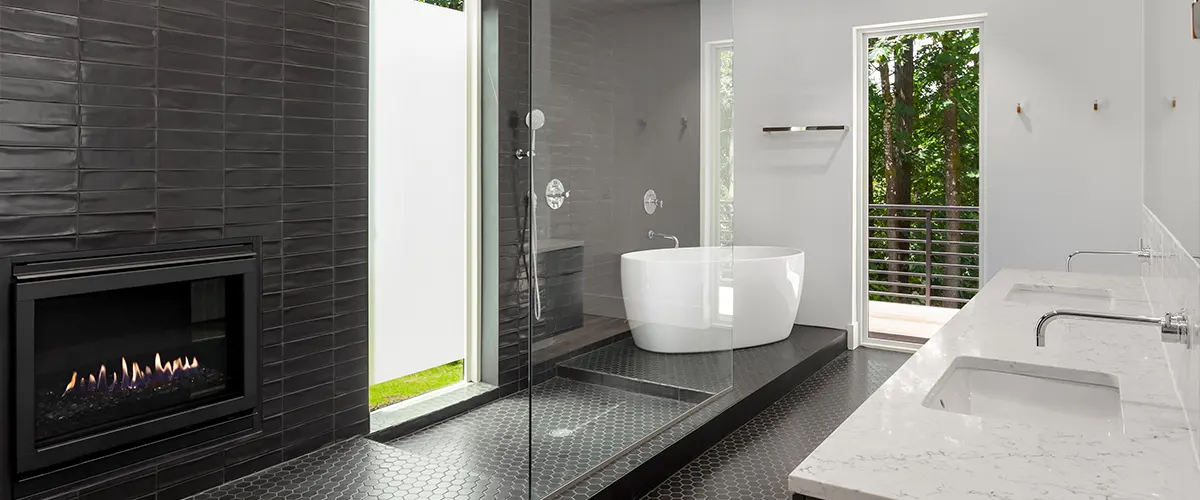 A bathroom with black tile surround for a shower and a free standing tub