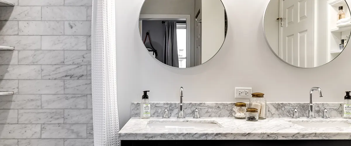 A quartz countertop with two round mirrors in a bath