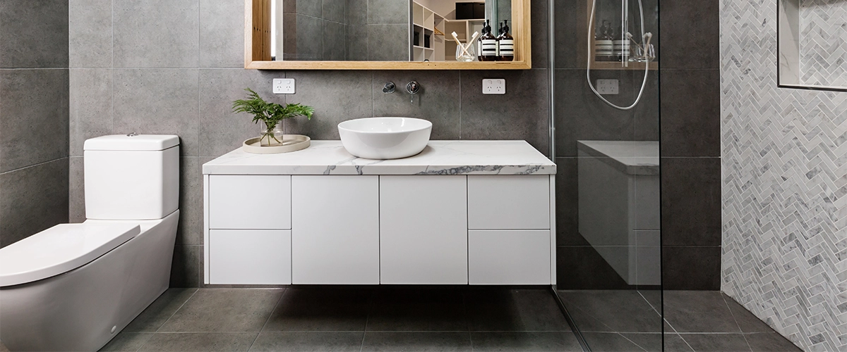 A modern wall mounted vanity in a bathroom with gray tile flooring and walls
