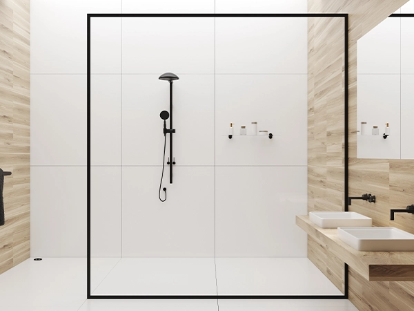 A glass walk-in shower with dark hardware