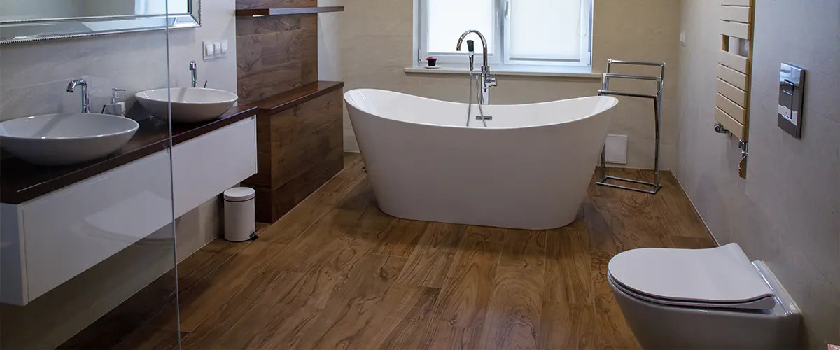 Wood flooring in a bathroom with a tub and simple vanity