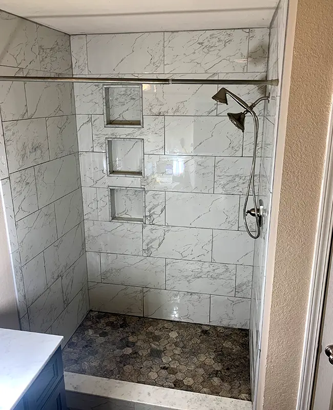 Hallway bathroom after removing tub and replacing it with a walk-in shower with marble tile and shower niches