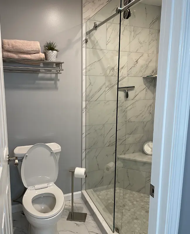 Shower remodel with simple glass enclosure and elegant marble tile