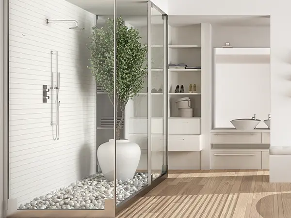 A glass walk-in shower in a bath with wood flooring