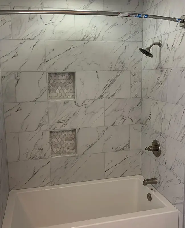 Guest bathroom after tub to shower conversion showing marble shower walls with elegant fixtures