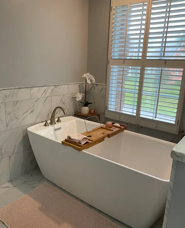 New freestanding tub in a light gray bathroom remodel with marble and new windows
