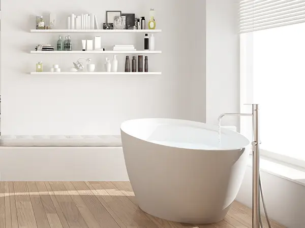 A free standing tub in a bath with wood flooring